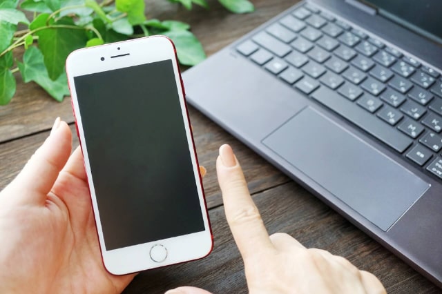 スマートフォンを操作する手とPC